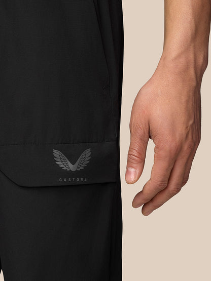 Close up of pocket area on black cargo trousers with bonded flap and Castore emblem.