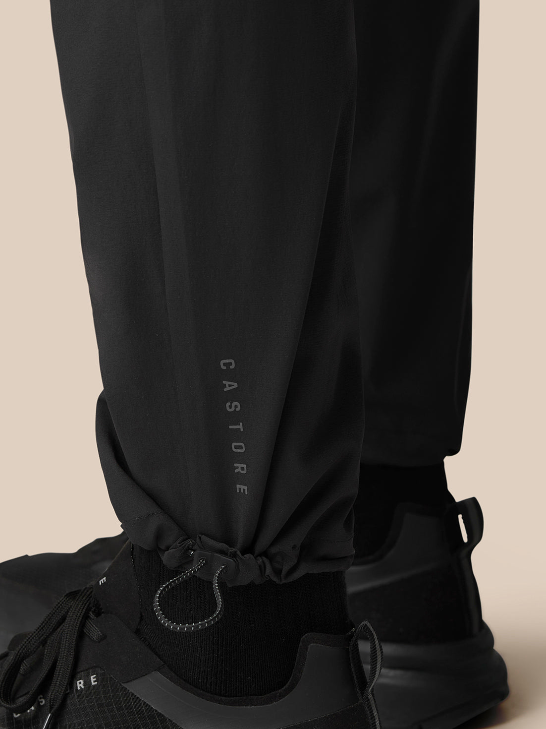 Close up of black Flex Lifestyle Cargo Trousers leg with cuff toggle and drawcord; Castore branding near the ankle.