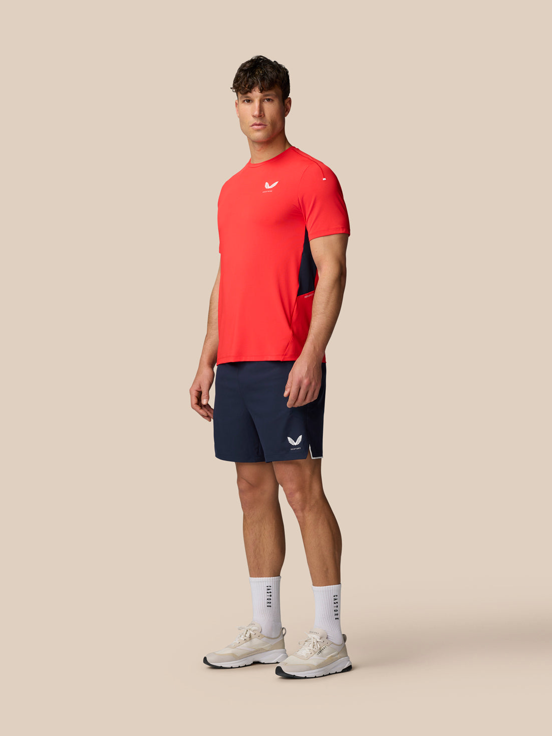 Male model in a red athletic tee and midnight navy Apex 6 inch shorts with white sneakers