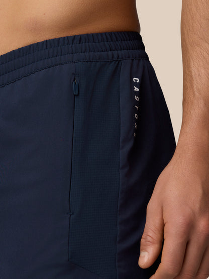 Close-up of navy Apex Training Shorts waist showing a zipped pocket and Castore branding along the side