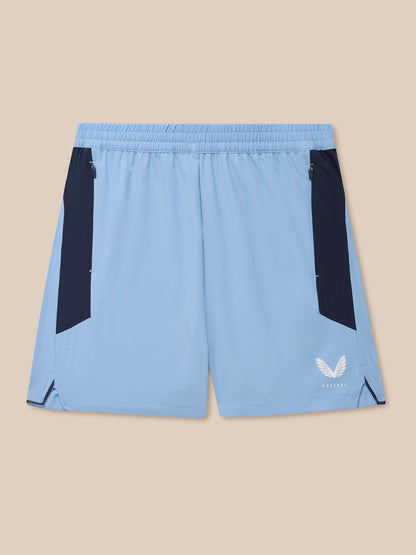 Sky blue Apex Training Shorts with navy side panels, zip pockets, and Castore logo on the leg