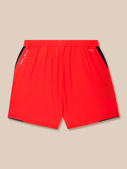 Red training shorts with navy side panels, Castore branding along the left leg and Protek text at the waistband.