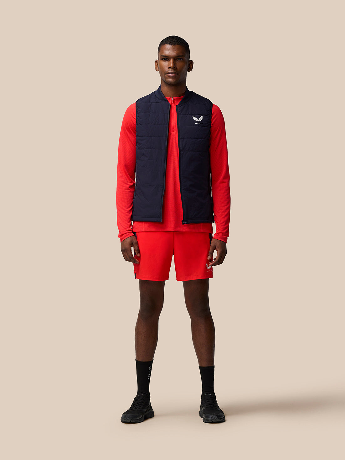 Male model wearing red Apex Training Shorts with a navy zip vest