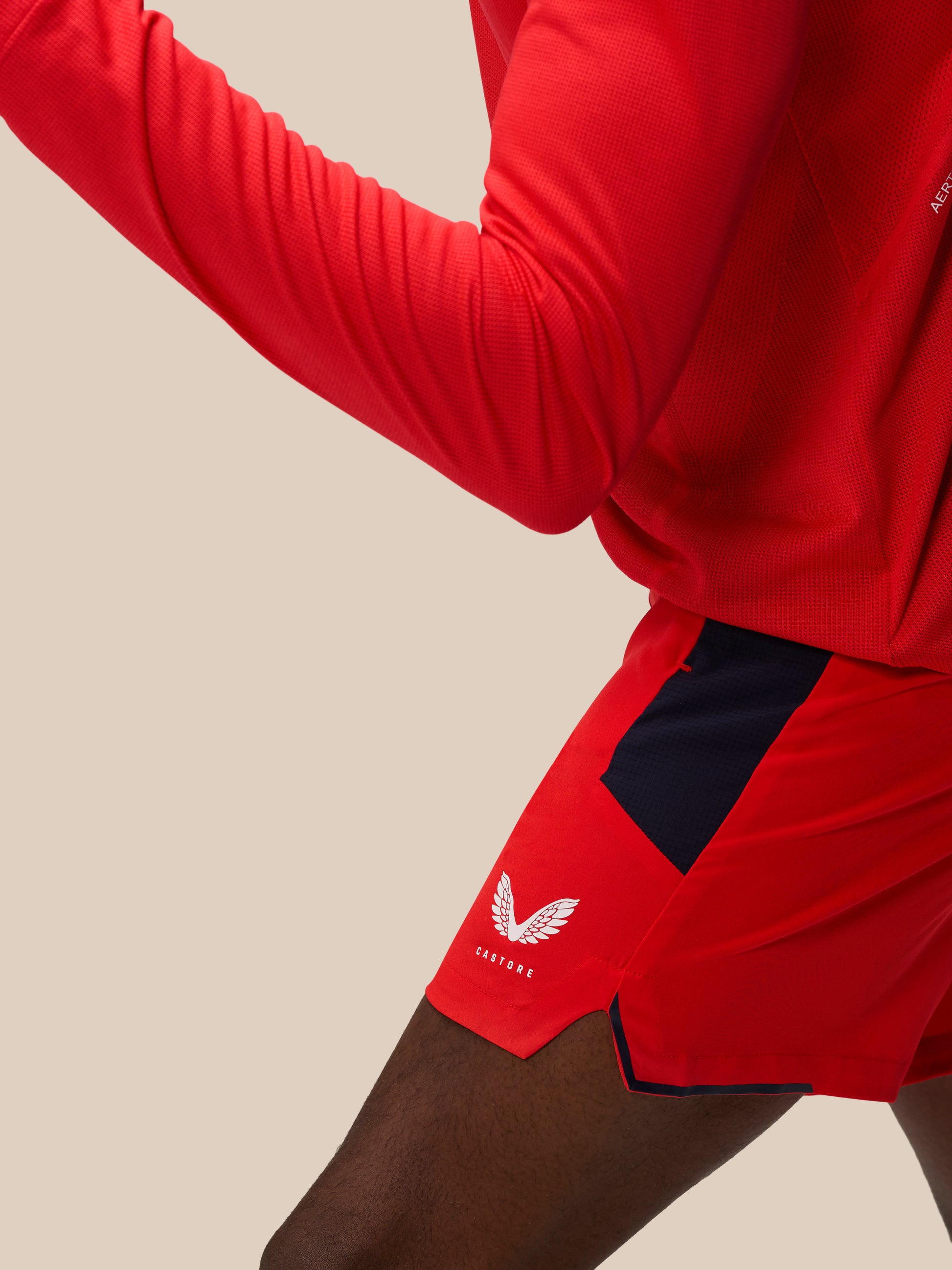 Back view of red shorts with navy side panels and a Castore logo on the hem