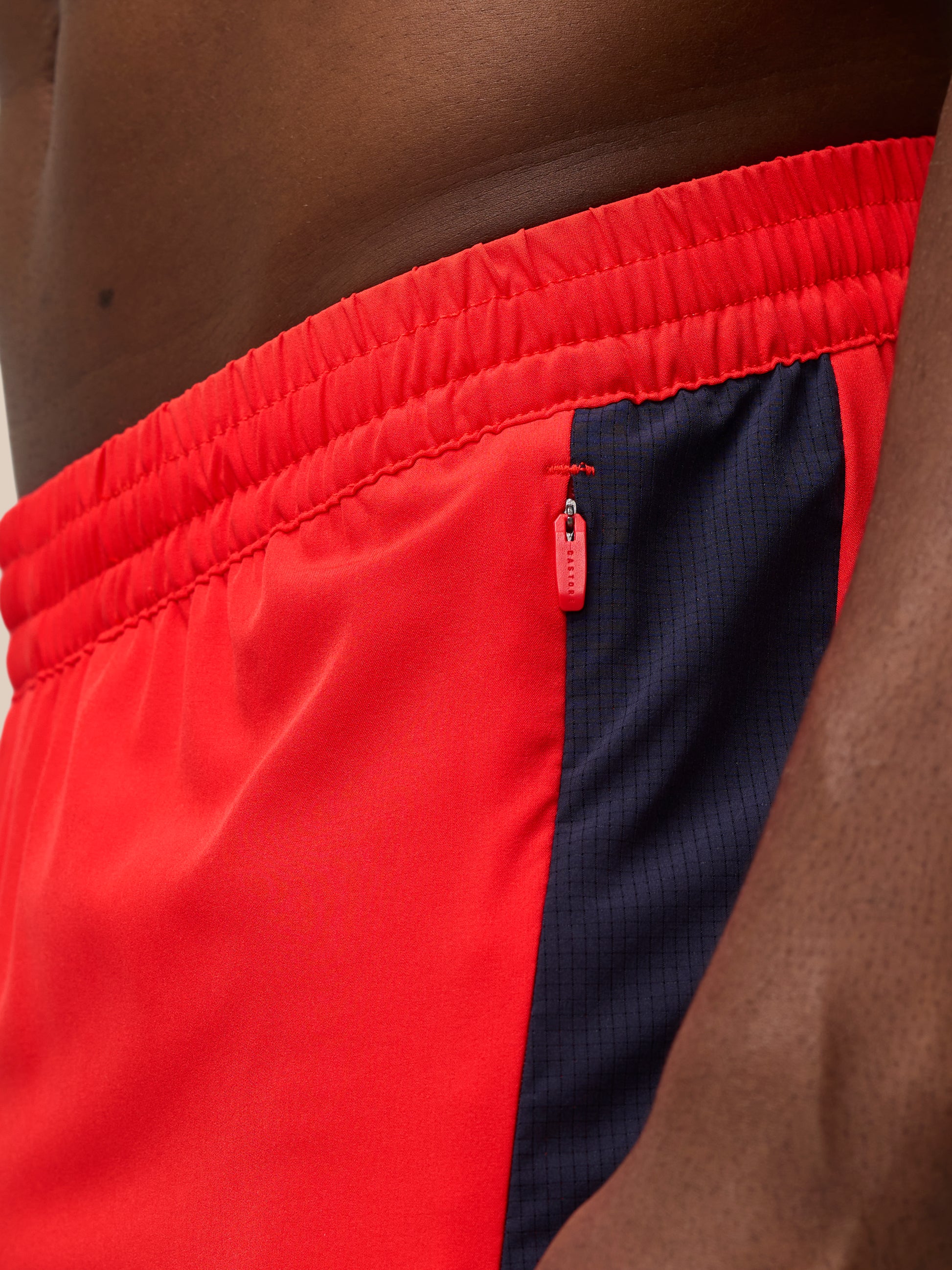 Close-up of red Apex Training Shorts waistband with elastic band and a zip pocket