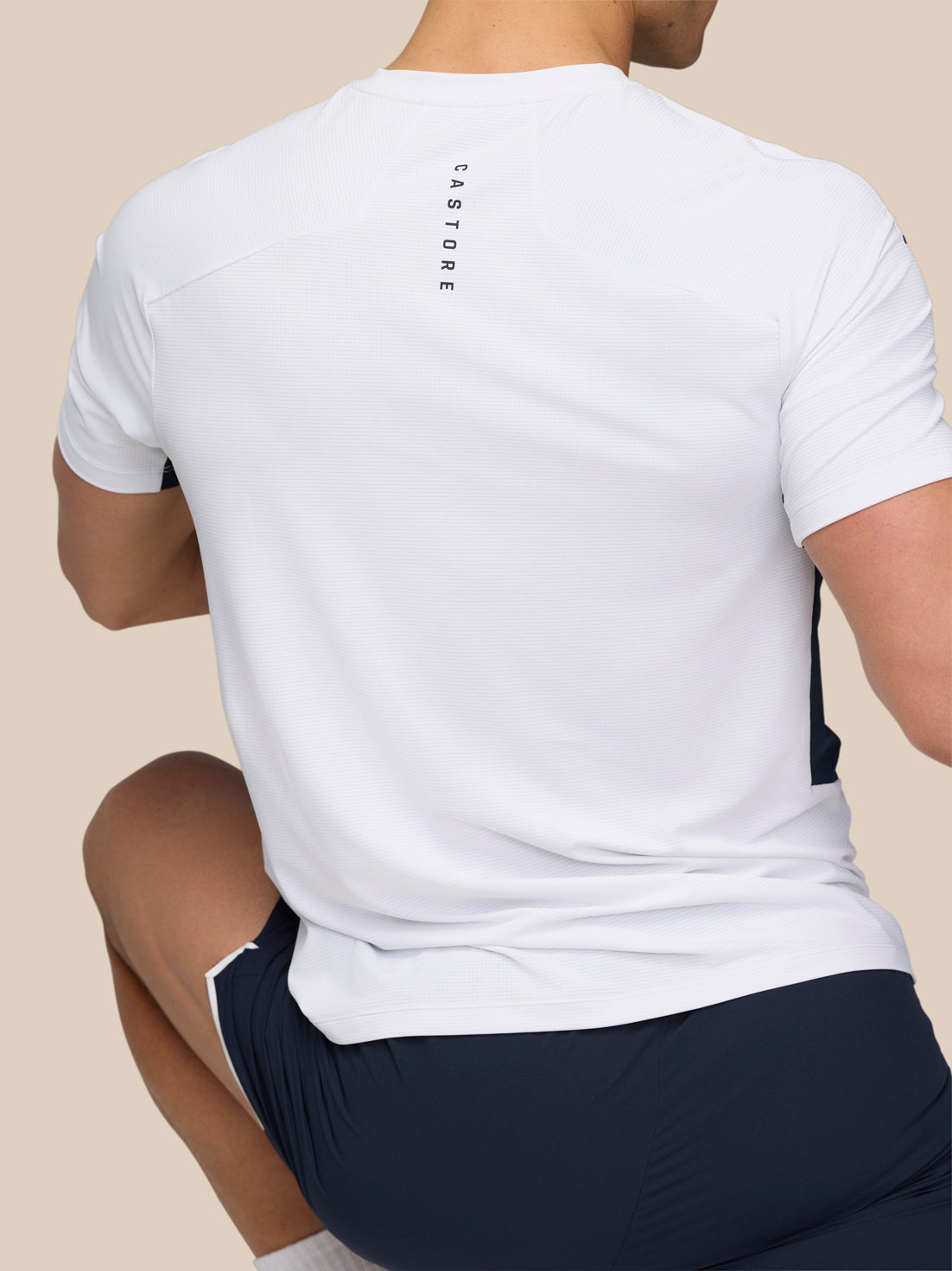 Back view of a man wearing a white Apex Training T-Shirt with vertical Castore branding on the upper back