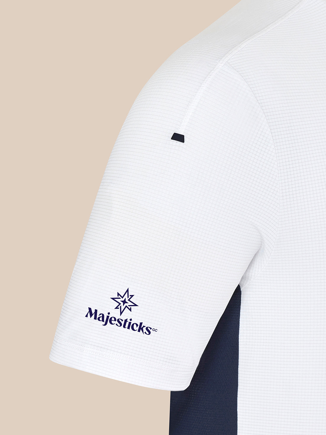White Majesticks golf T-shirt sleeve close up showing grid fabric navy side panel and Majesticks logo on the sleeve