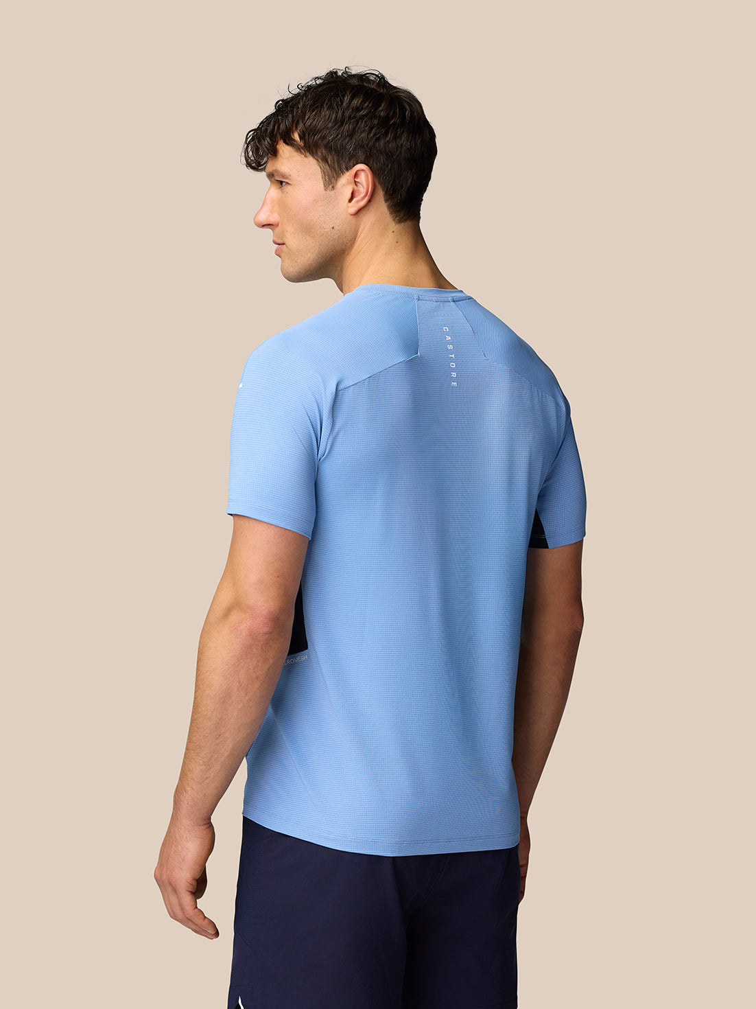 Back view of a model wearing Sky Blue Apex Training T-Shirt with vertical branding on the upper back