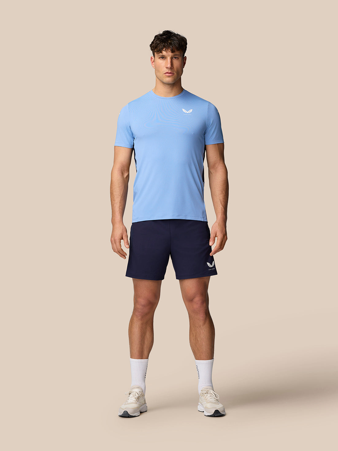 Male model in sky blue Apex Training T-Shirt with navy shorts; white Castore logos on chest and left leg.