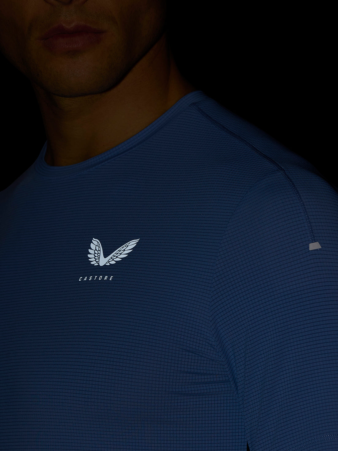 Close up of a man wearing a sky blue Apex Training T-Shirt with a white Castore logo on the chest.