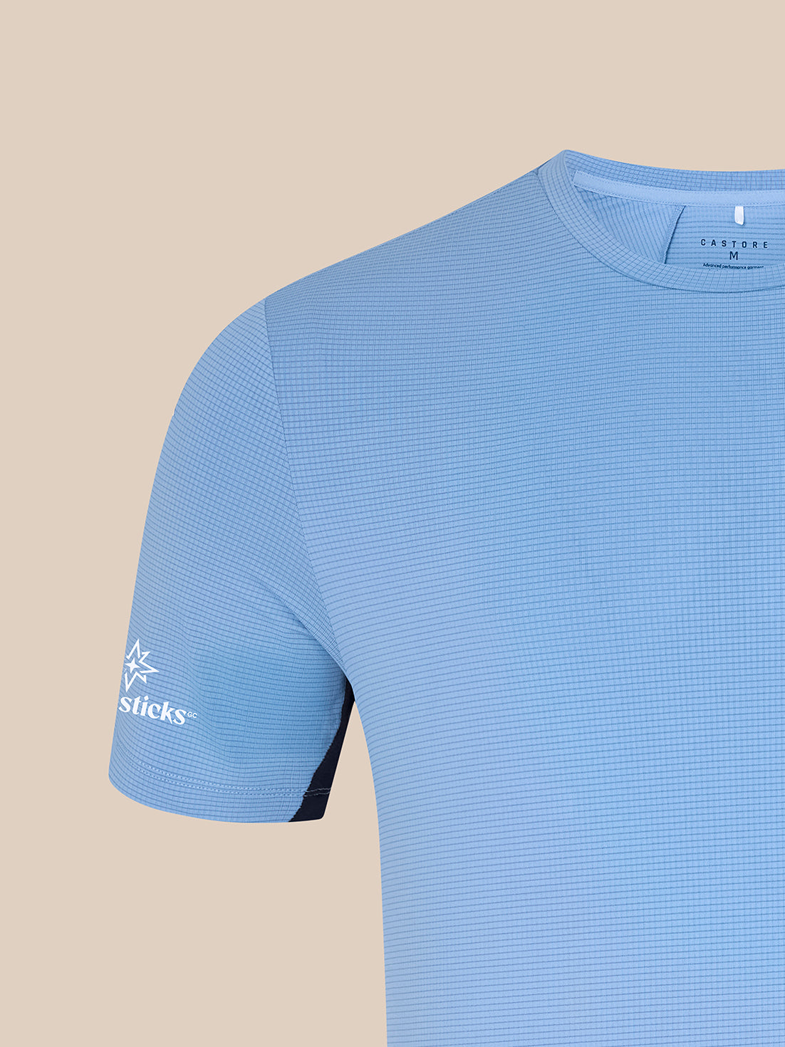 Close-up of sky blue Majesticks T-Shirt fabric with a fine grid texture and a white Castore branding at the neckline