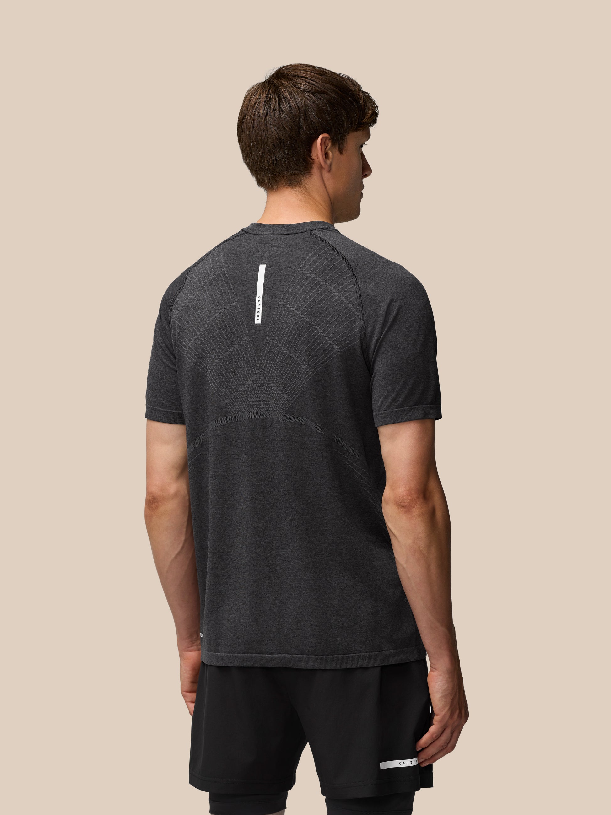 Back view of Flow Training T Shirt with a vertical white logo strip on the upper back and hem details