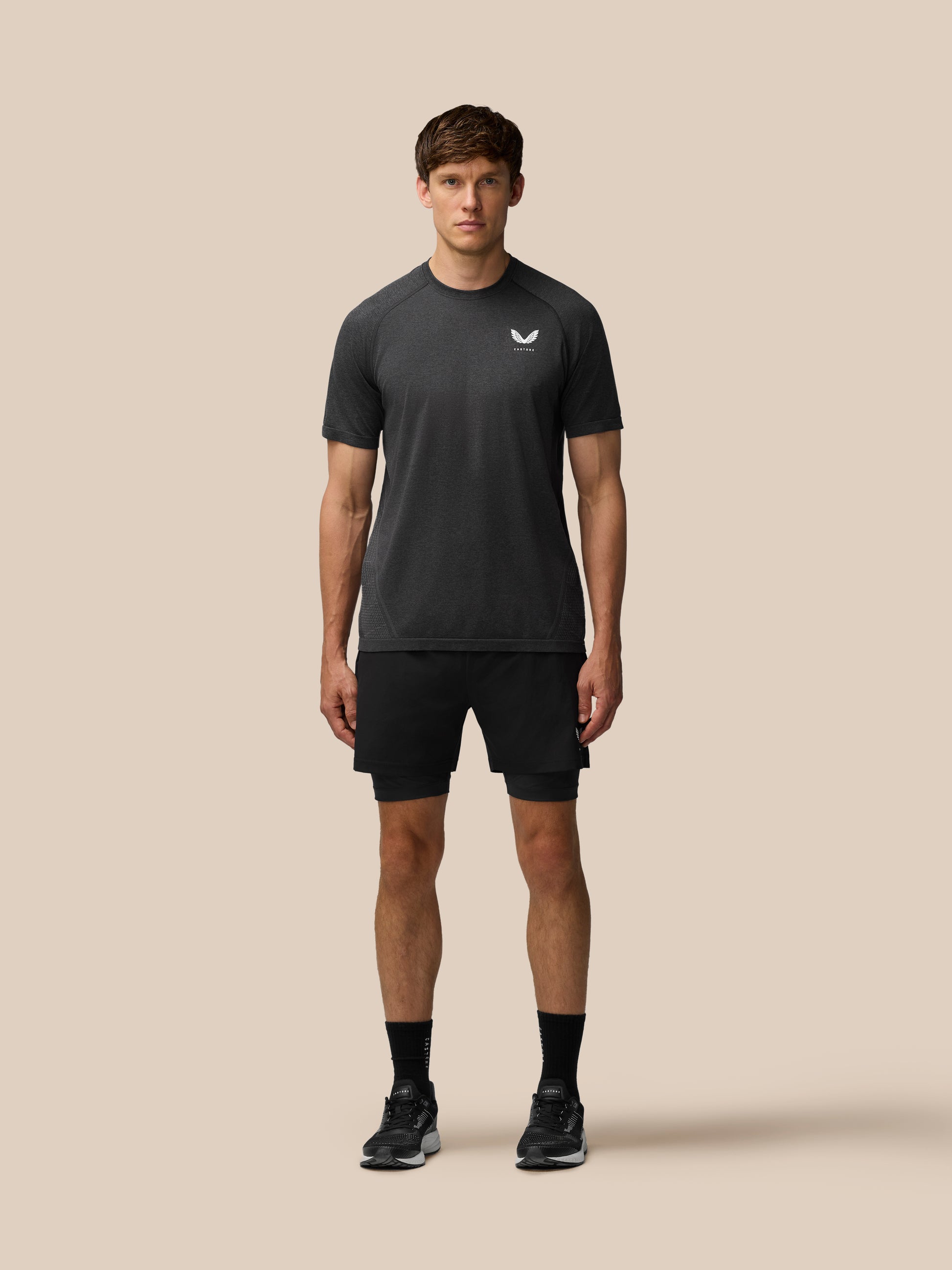 Flow Training T-Shirt in black worn by a male model front view showing seamless knit and small left chest logo