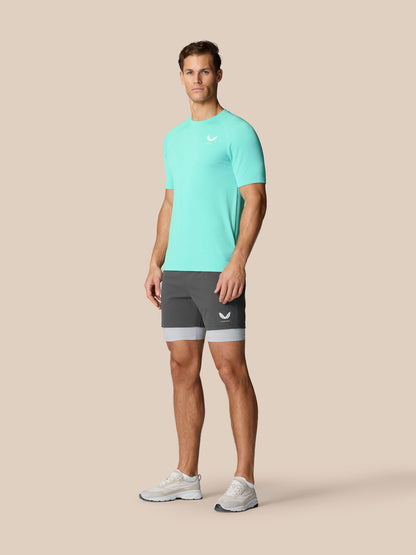 Flow Training T-Shirt in light aqua worn by a man with grey shorts and white sneakers.