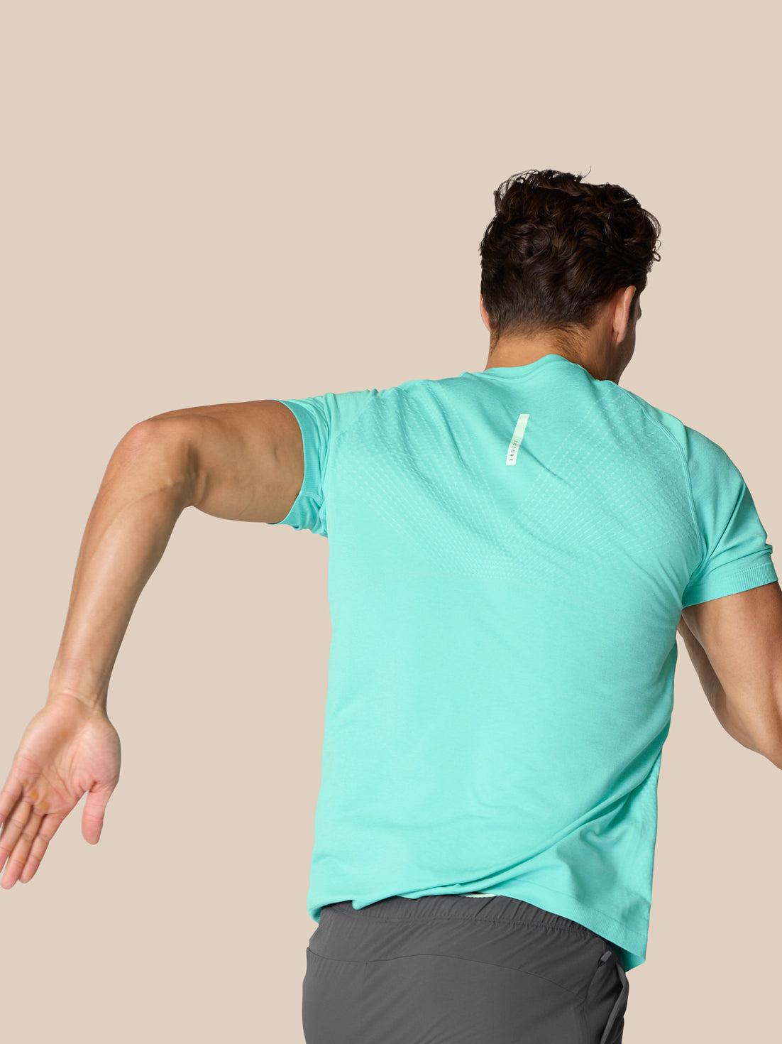 Back view of a man in light aqua Flow Training T Shirt with a small white logo on the upper back