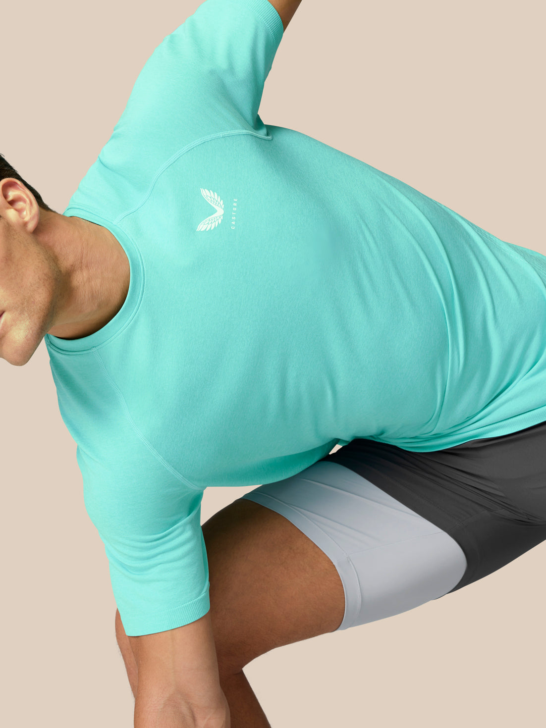 Side view of a man wearing light aqua Flow Training T Shirt with a white logo on the chest