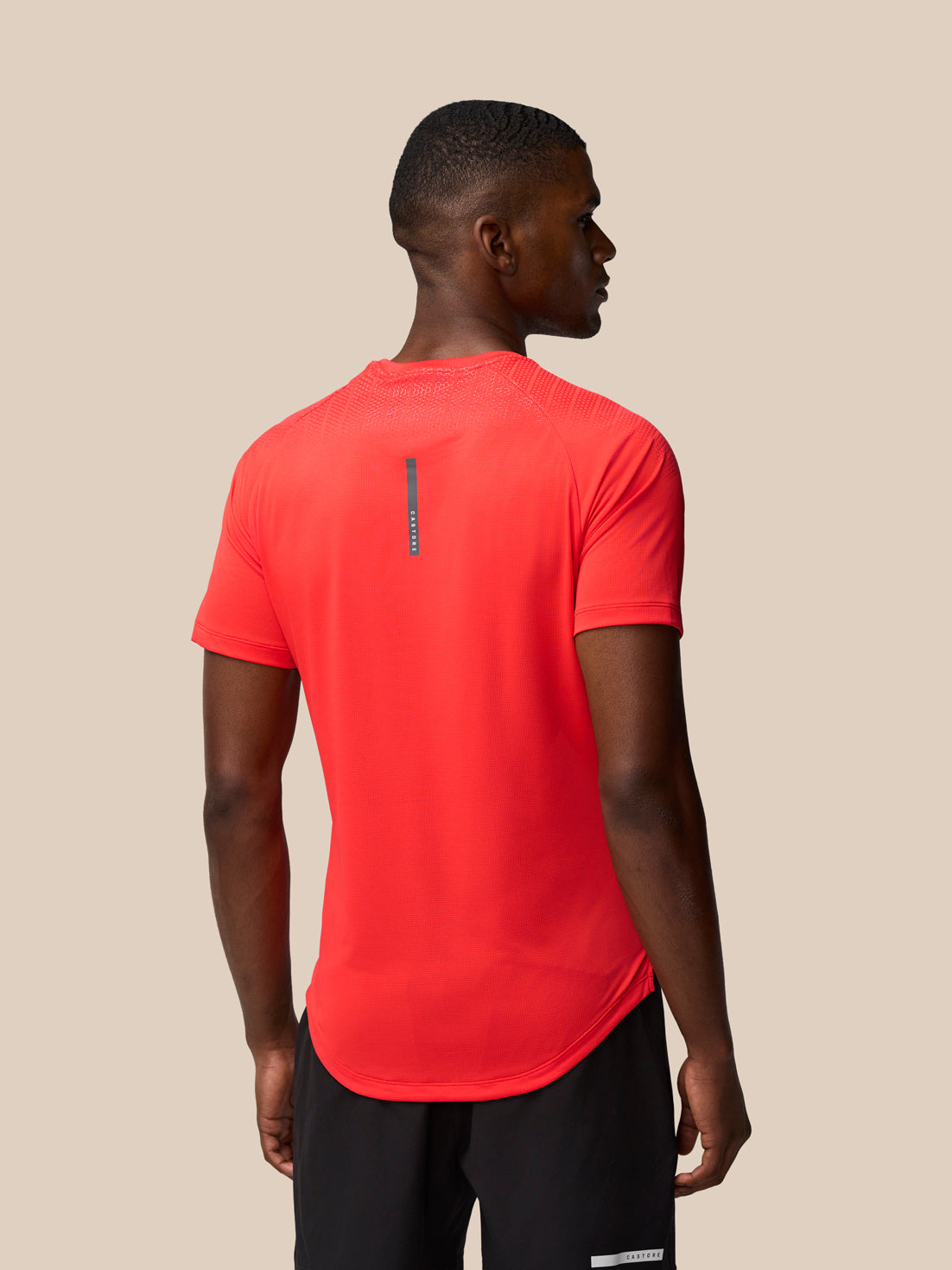 Back view of male model in red Flow Training Muscle Grip T-Shirt showing a vertical reflective stripe on the upper back