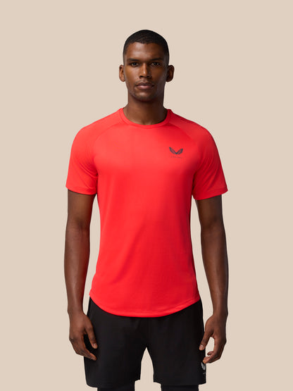 Male model wearing Flow Training Muscle Grip T-Shirt in Poppy red with a small logo on chest, black shorts