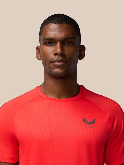Portrait of a man wearing a bright red Flow Training Muscle Grip T-Shirt with a winged left chest logo