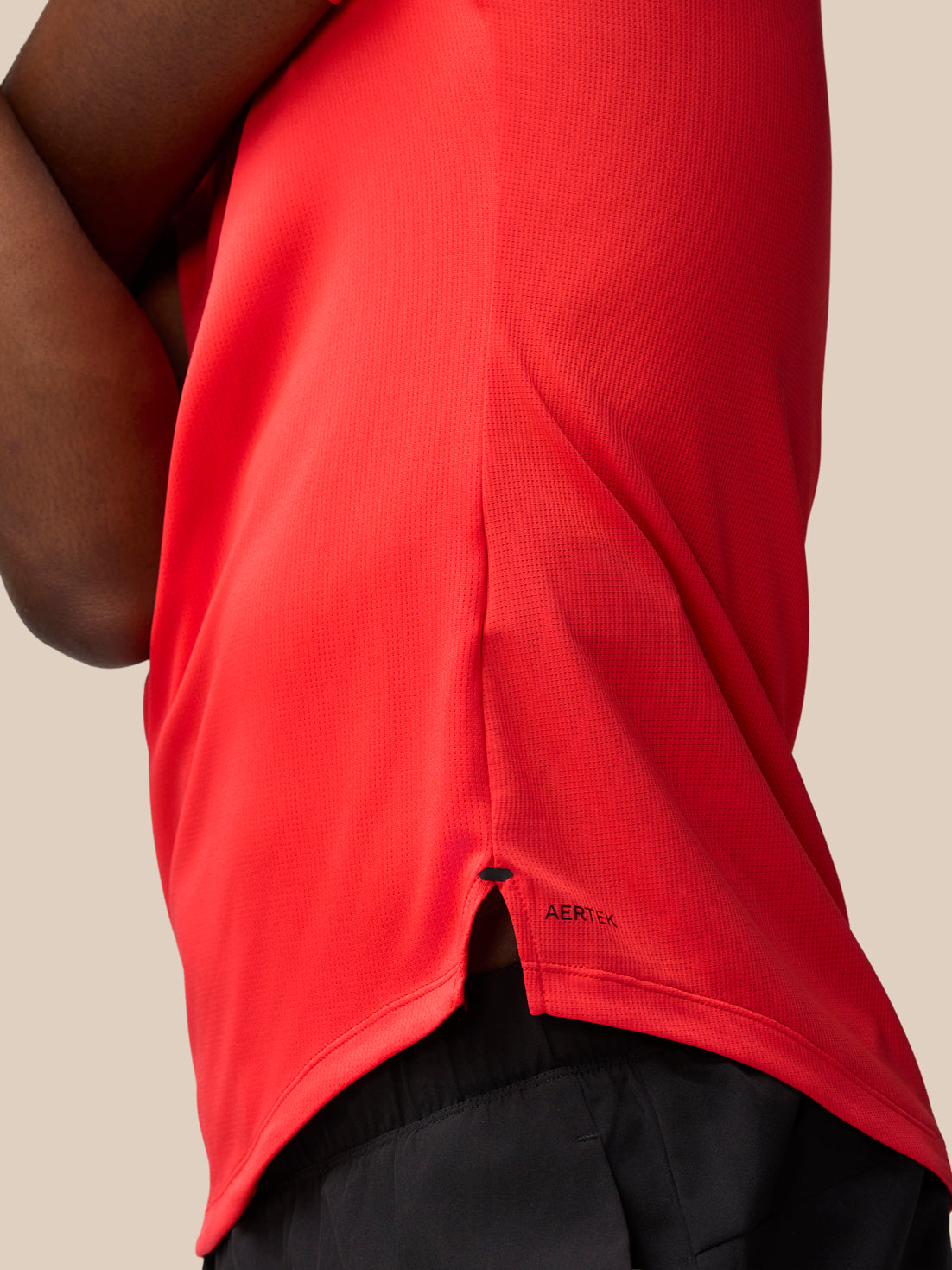Close up of the red muscle grip T-shirt showing vented hem and AerTek label