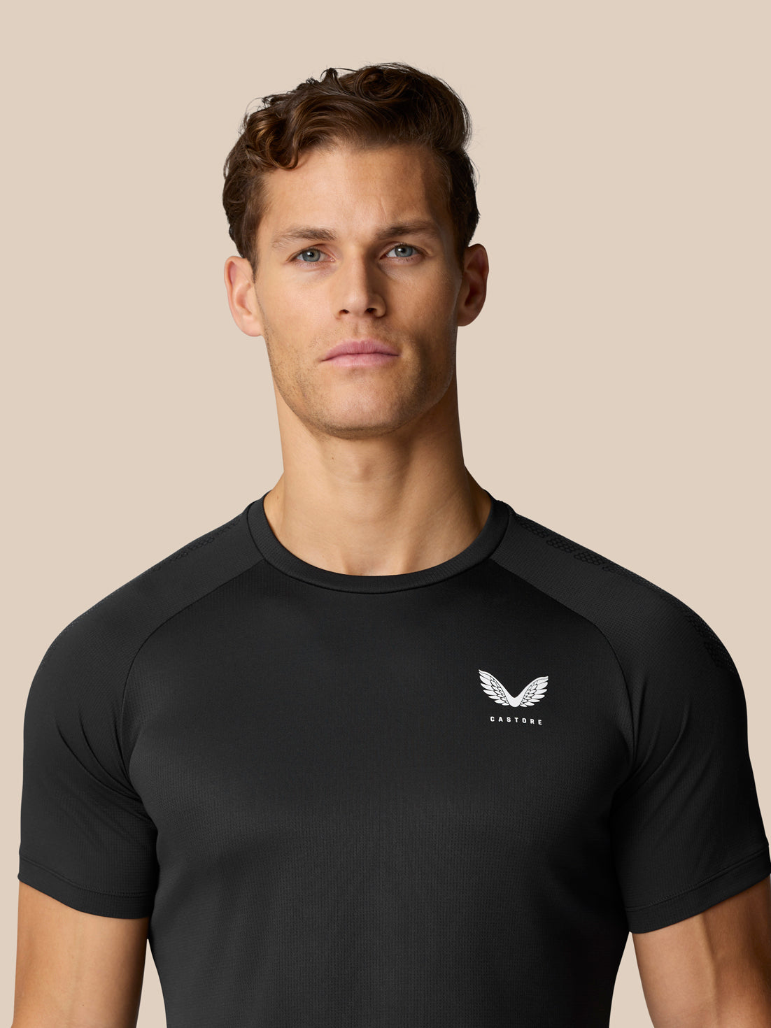 Close up of a man in black Flow Muscle Grip T Shirt, logo on chest visible.