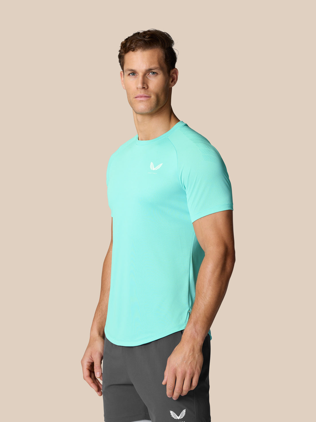 Male model wearing Flow Training Muscle Grip T-Shirt in Light Aqua front view with chest logo and slim athletic fit.