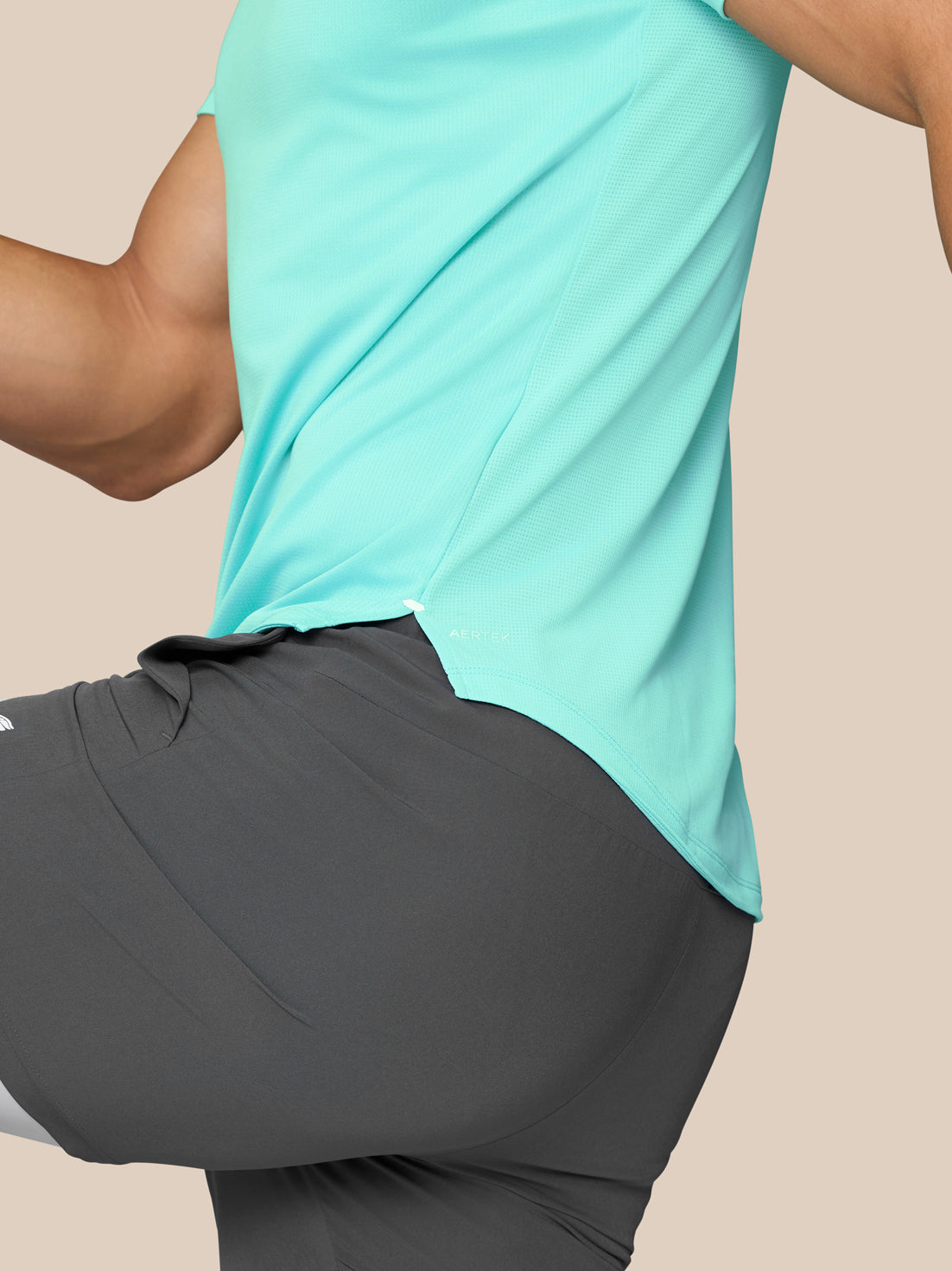 Side profile of a man in light aqua Flow Training Muscle Grip T Shirt with curved hem and AerTek logo at the hem