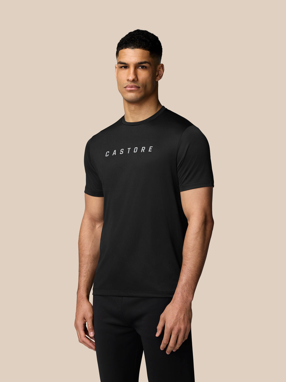 Side profile of a man in a black Castore graphic training T shirt showcasing the front logo