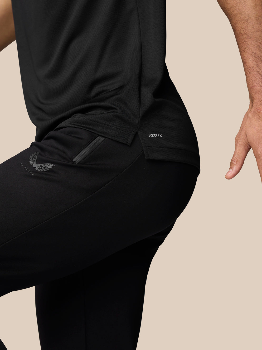 Close-up of a black athletic top layered over black shorts with a zip pocket and AerTek branding.