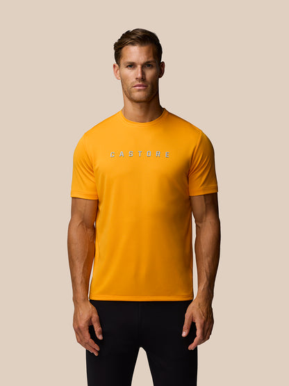 Male model wearing bright mango orange graphic training T shirt with Castore logo across the chest