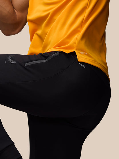 Side view of a bright mango training T-shirt tucked over black athletic pants with split hem and AerTek label.