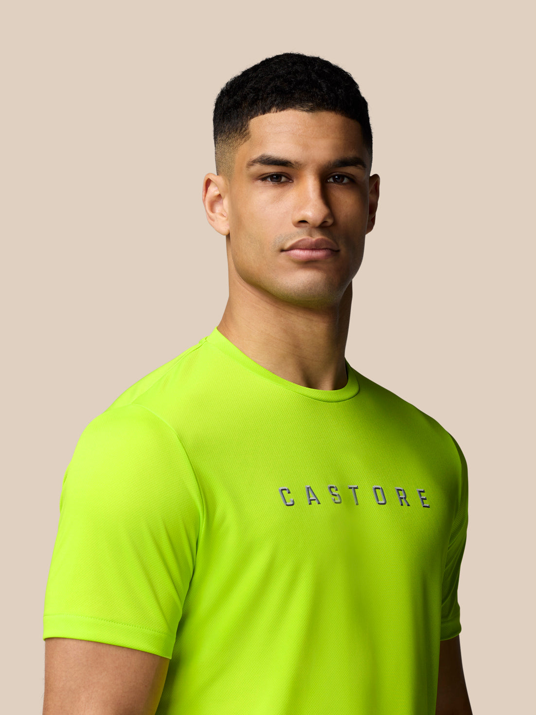 Close-up of male model wearing neon lime Castore Graphic Training T-Shirt with crew neck and a bold logo on the chest