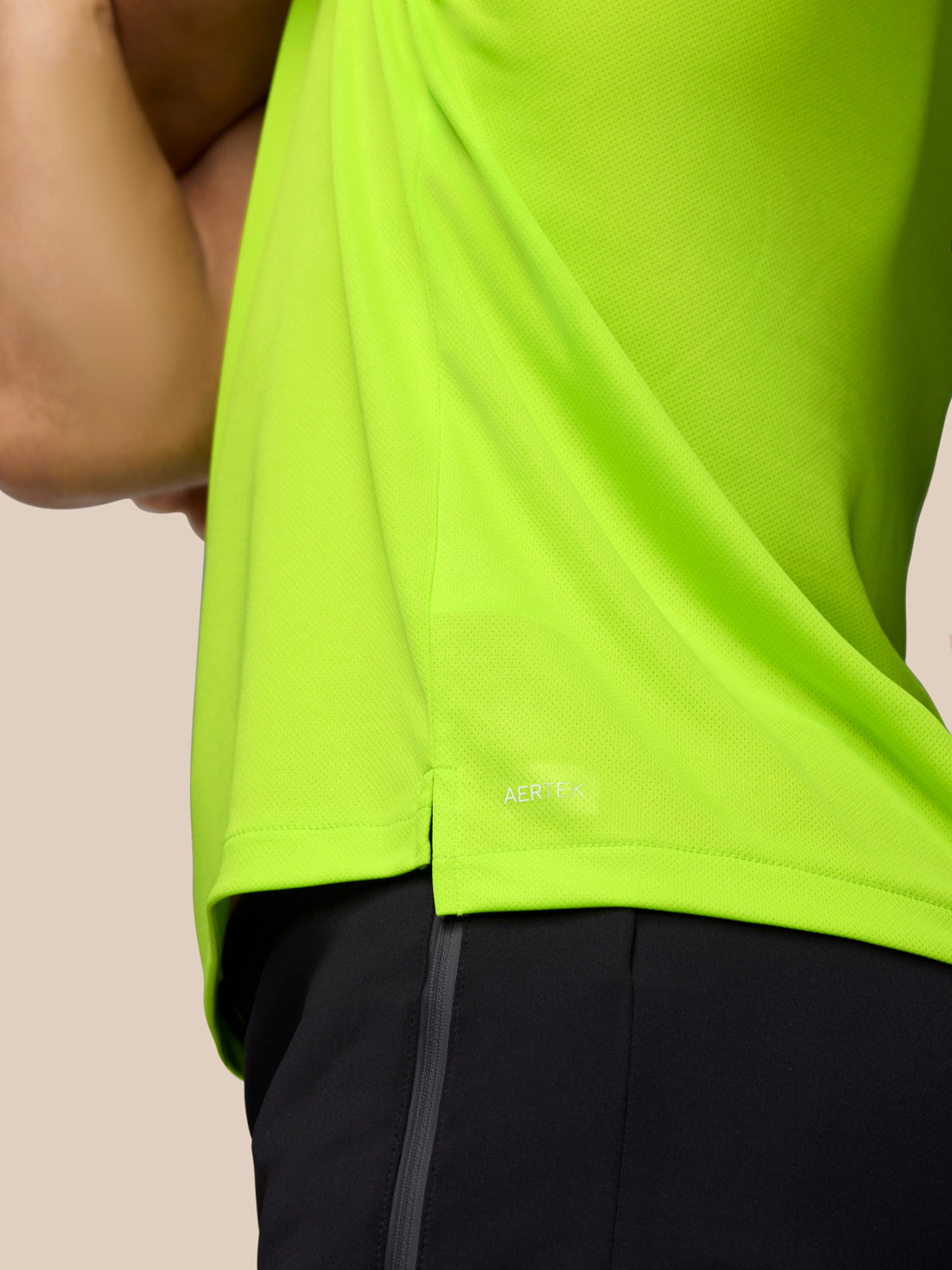 Close-up of neon lime fabric with an AerTek label near the hem and dark pants visible