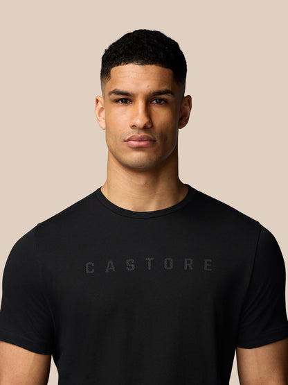 Male model wearing a black Castore graphic T-shirt with a crew neck drop shoulders and regular fit