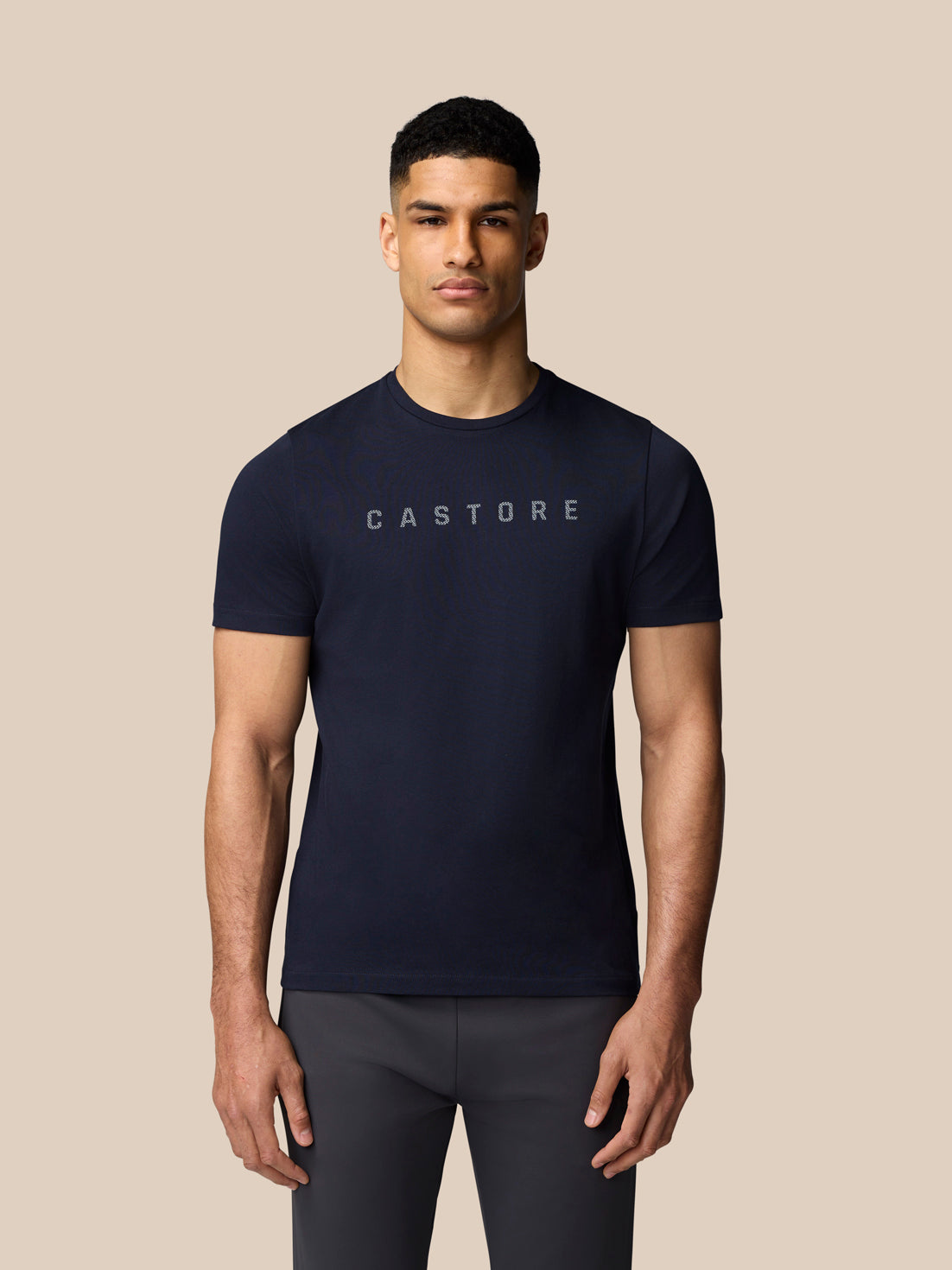 Torso shot of a man wearing a navy Castore graphic T-shirt with crew neck short sleeves and a front logo.