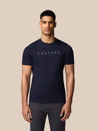 Torso shot of a man wearing a navy Castore graphic T-shirt with crew neck short sleeves and a front logo.