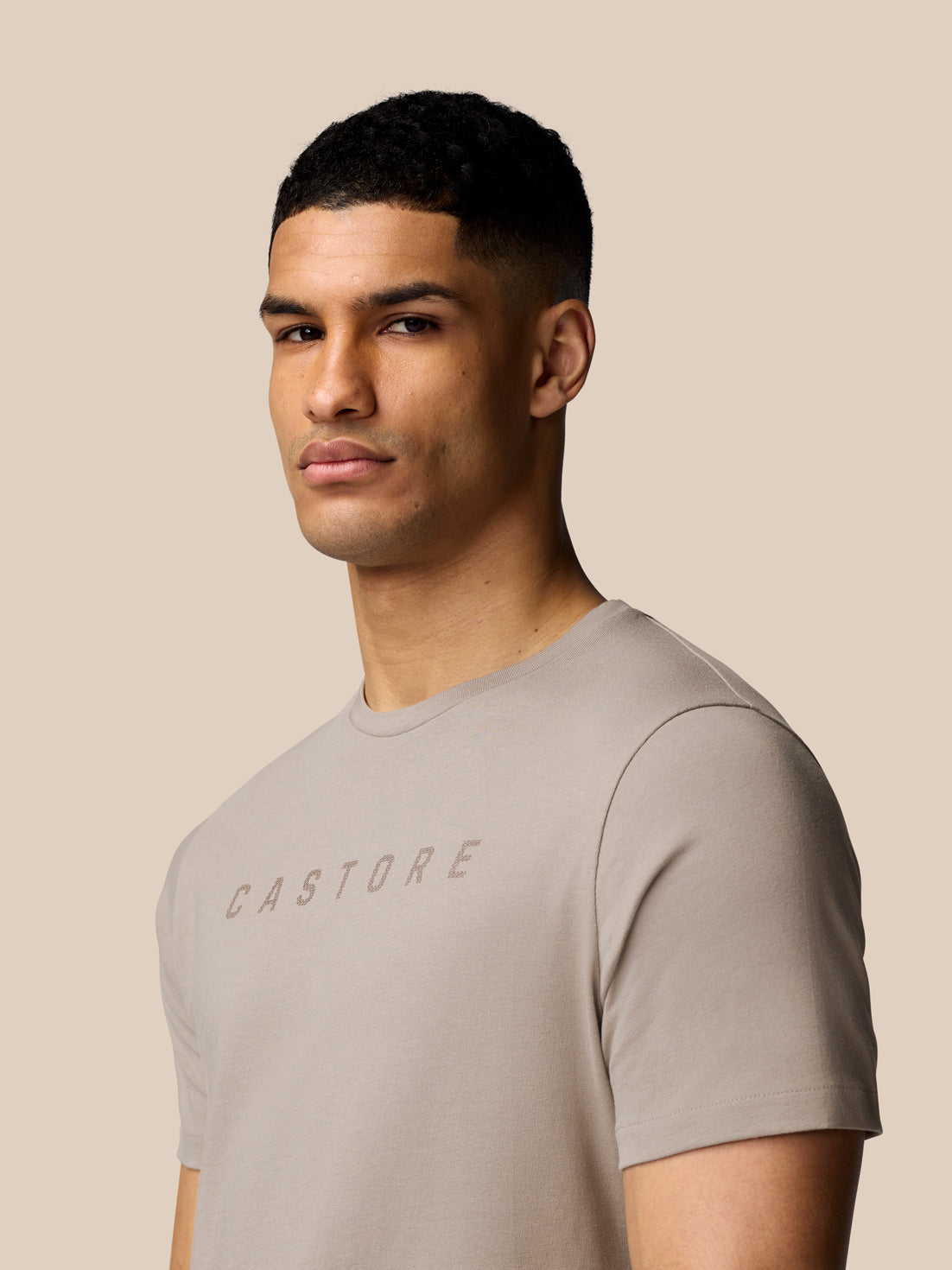 Close-up of male model wearing the Rock Grey graphic T shirt with Castore logo.