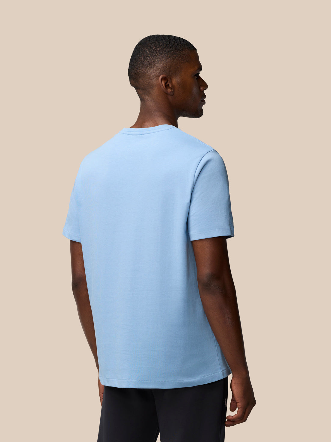 Back and side view of a man in a sky blue graphic training T shirt highlighting the relaxed fit.