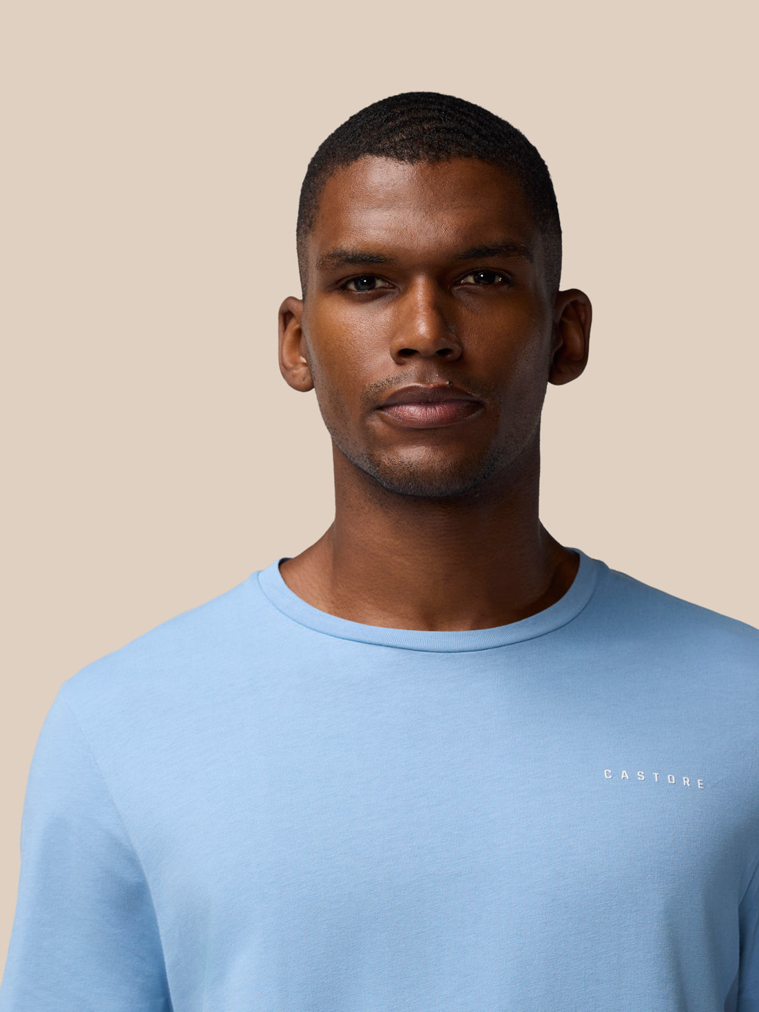 Close-up of a man wearing a sky blue graphic training T shirt with CASTORE logo on the chest.