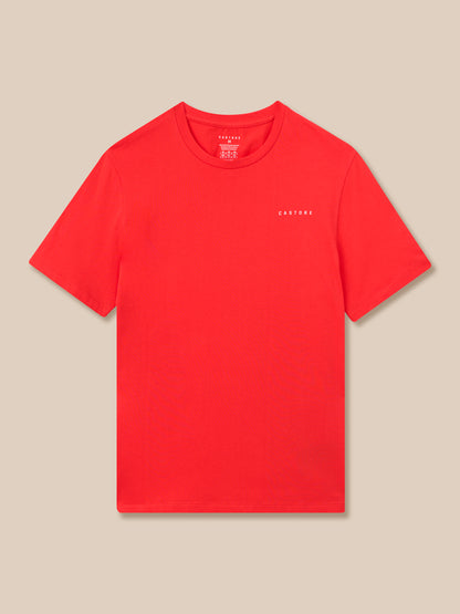 Red Graphic Training T‑shirt laid flat on a tan background with a small white Castore logo on the left chest