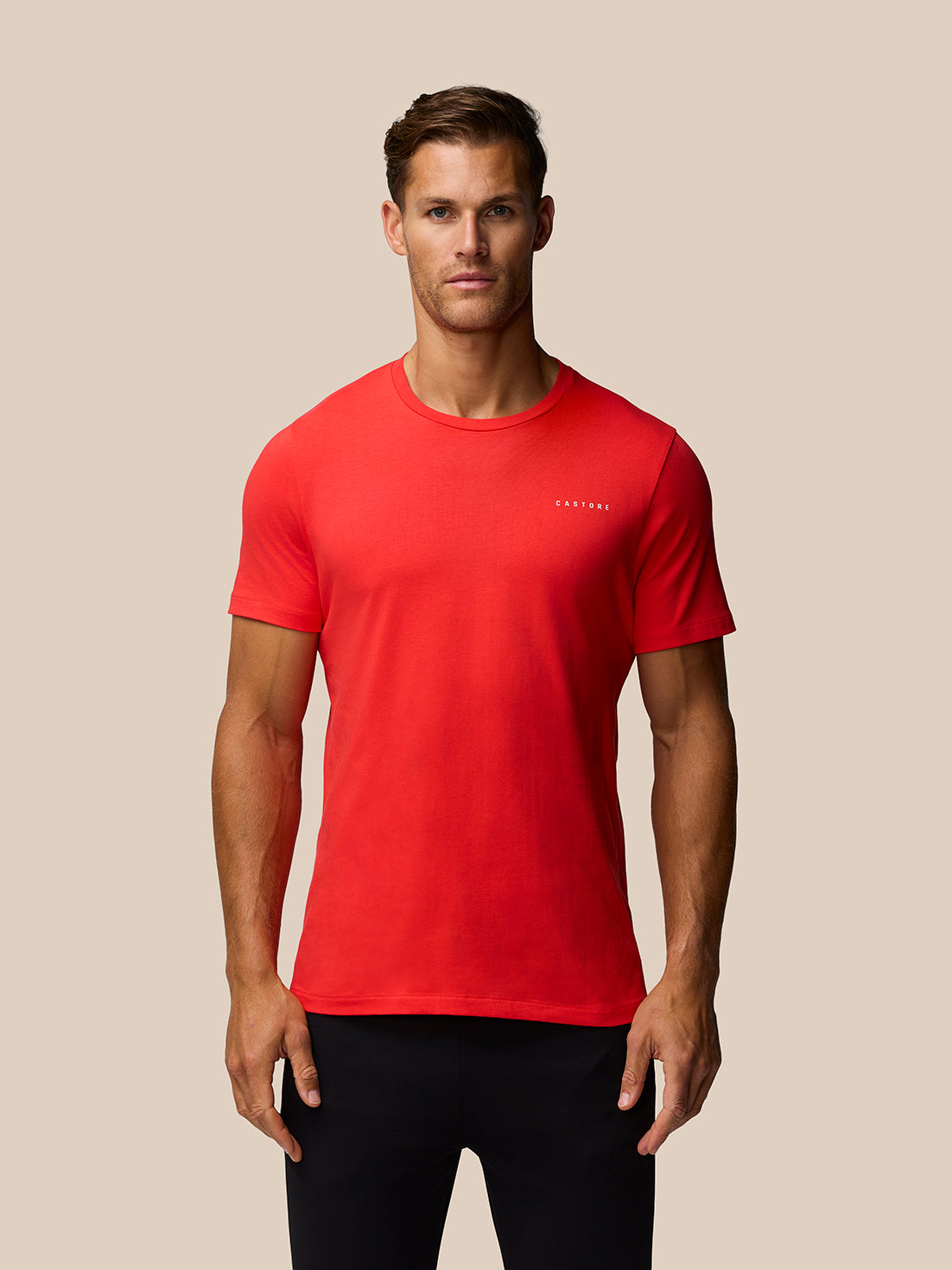 Front view of a man in a bright red graphic training t shirt with Castore logo on chest