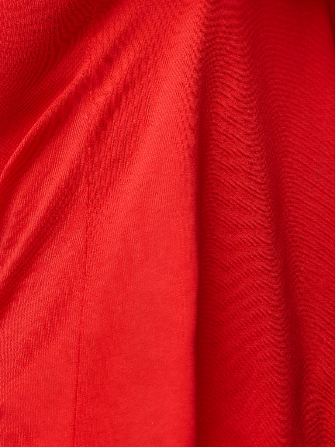 Close up of red fabric showing knit texture and a seam