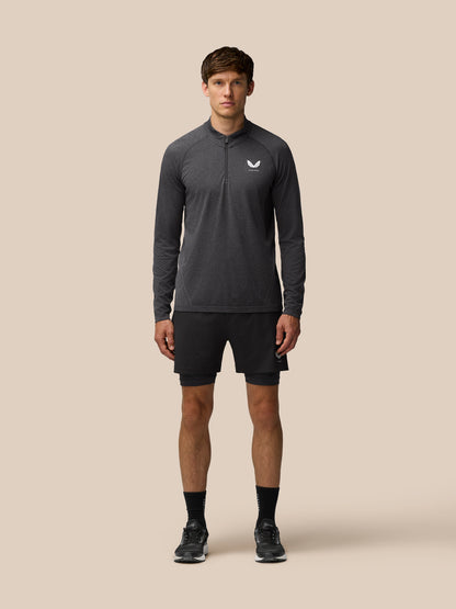 Full-body front view of a male model wearing a dark gray Flow Training 1/4 Zip Top with chest zipper and Castore logo against a neutral background
