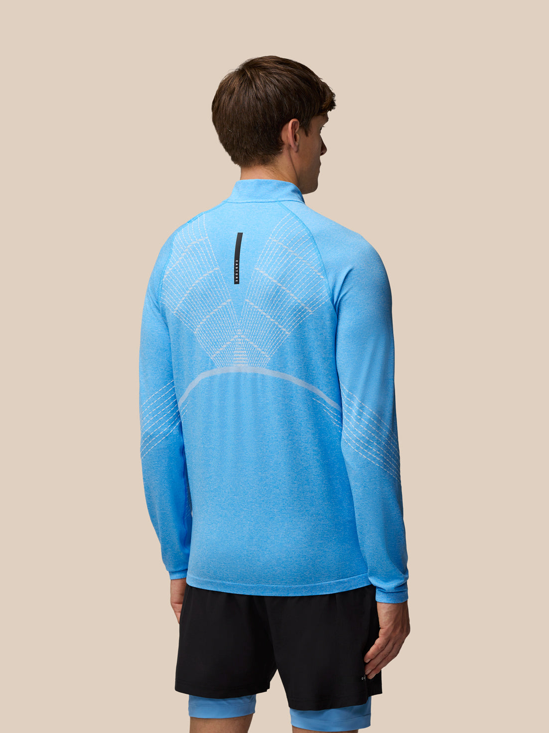 Back view of blue Flow Seamless quarter zip long sleeve top with knit pattern on back and sleeves.