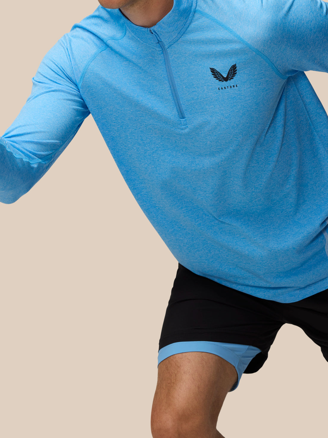 Model wearing Flow Seamless Quarter Zip Long Sleeve Top in cool blue front view with Castore logo on chest.