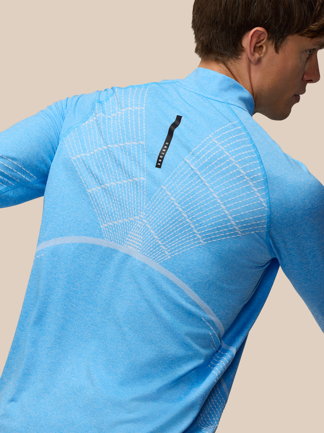 Back view of Flow Seamless Quarter Zip Long Sleeve Top in Cool Blue showing knit pattern and Castore logo tab.