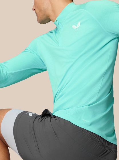 Side view of Flow Training 1/4 Zip Top in light aqua with Castore logo on the left chest and subtle back panel texture.