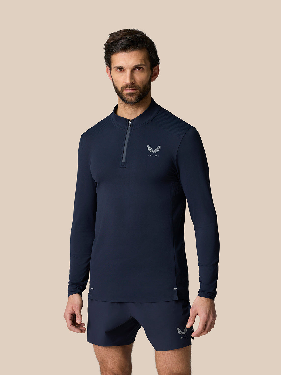 Male model wearing midnight navy Zone Training 1/4 Zip Top with high neck and front zip and chest logo