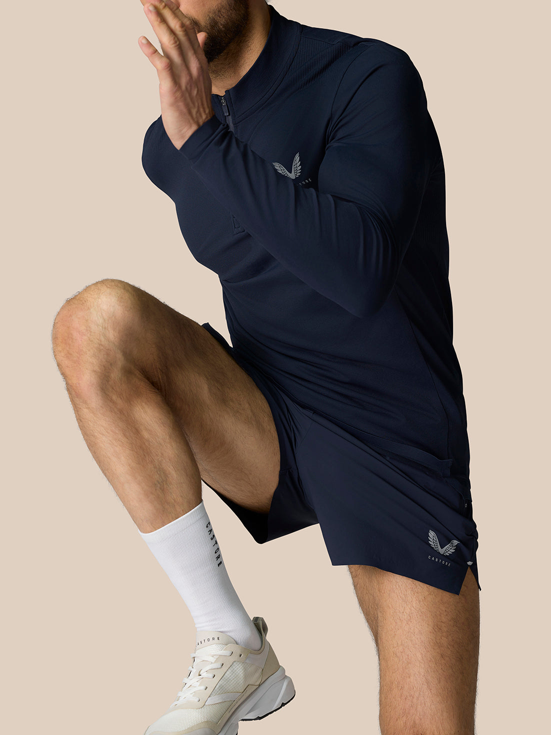 Male model in navy Zone Training 1/4 Zip Top in motion with chest logo and zip neck