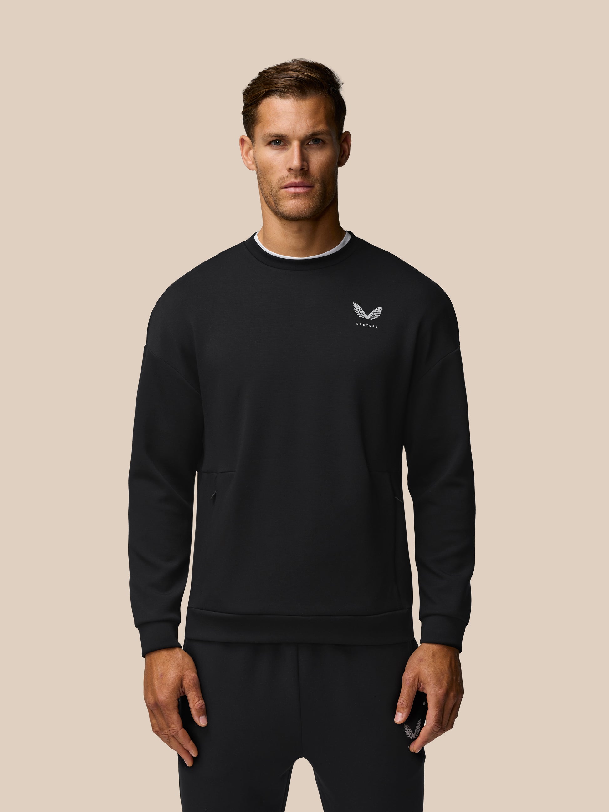Front view of a man in a black Travel Lifestyle Sweatshirt focusing on the left chest logo and relaxed fit.